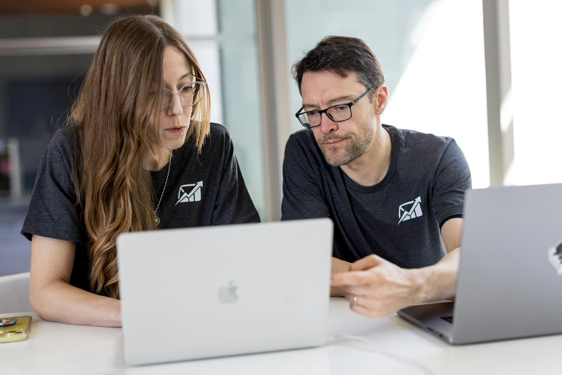 Two colleagues working through a plan on their laptops